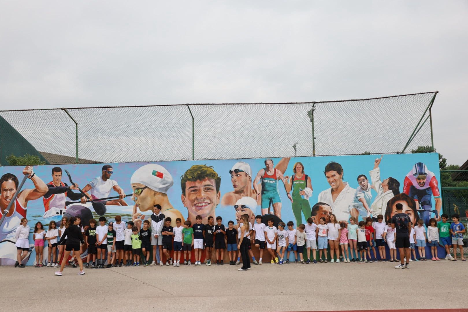 As fundadoras do Grupo Solutions com um grupo de crianças junto a um mural